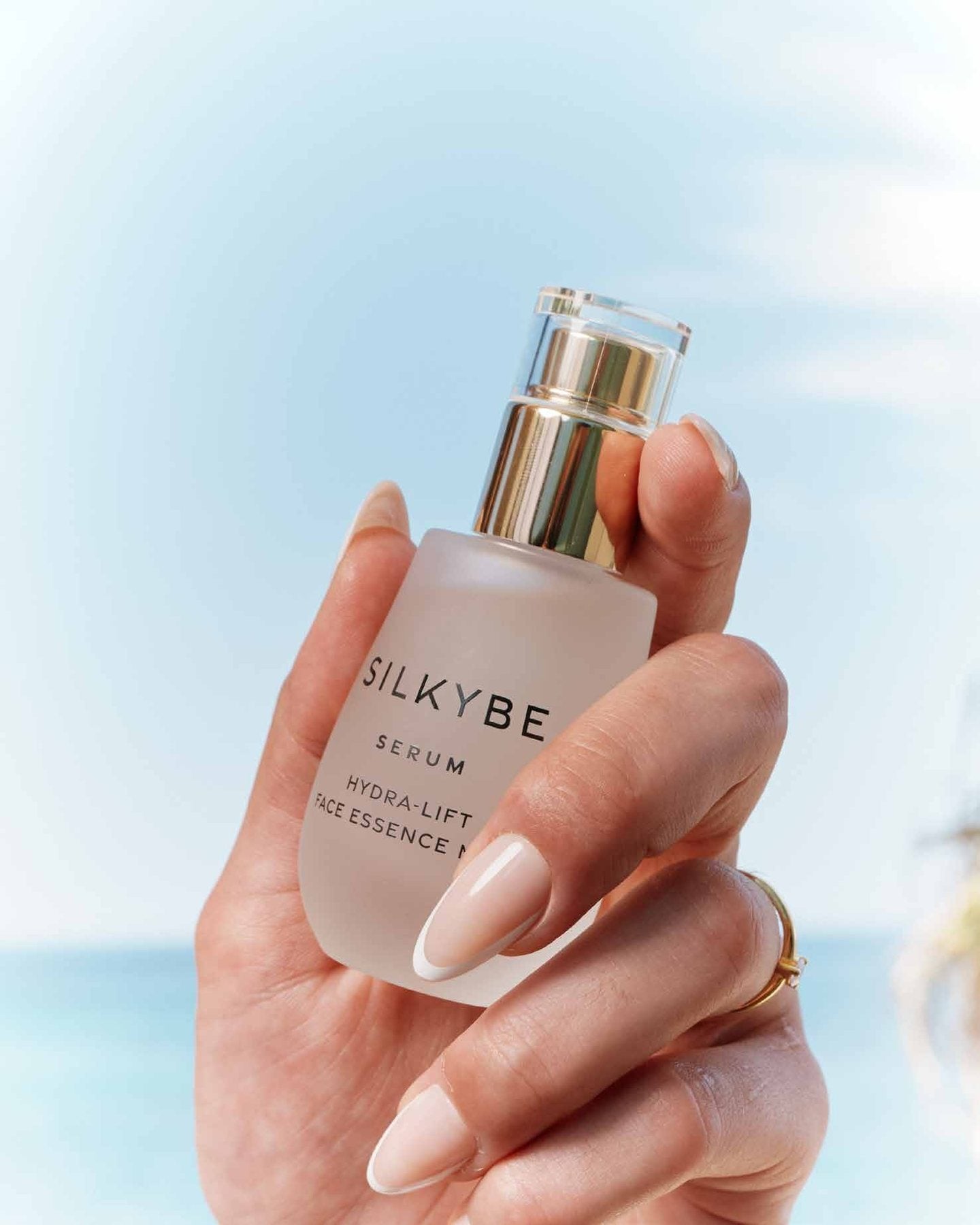 Mano che tiene il serum Silkybe contro il cielo